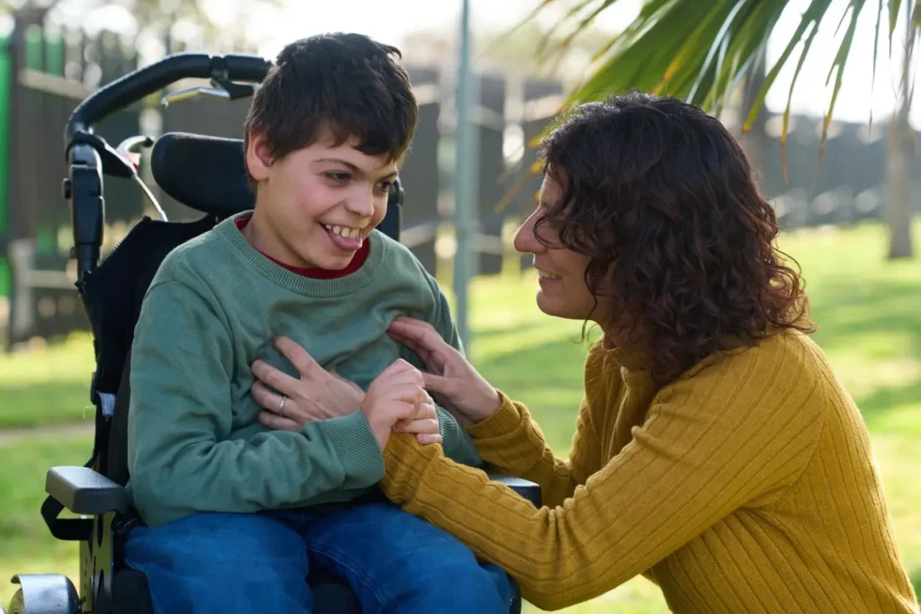 Disabled boy in wheelchair smiling with mum