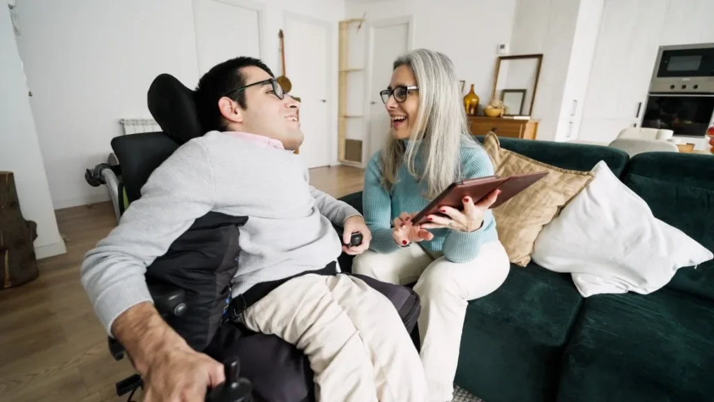 Disabled man in wheelchair laughing with support worker